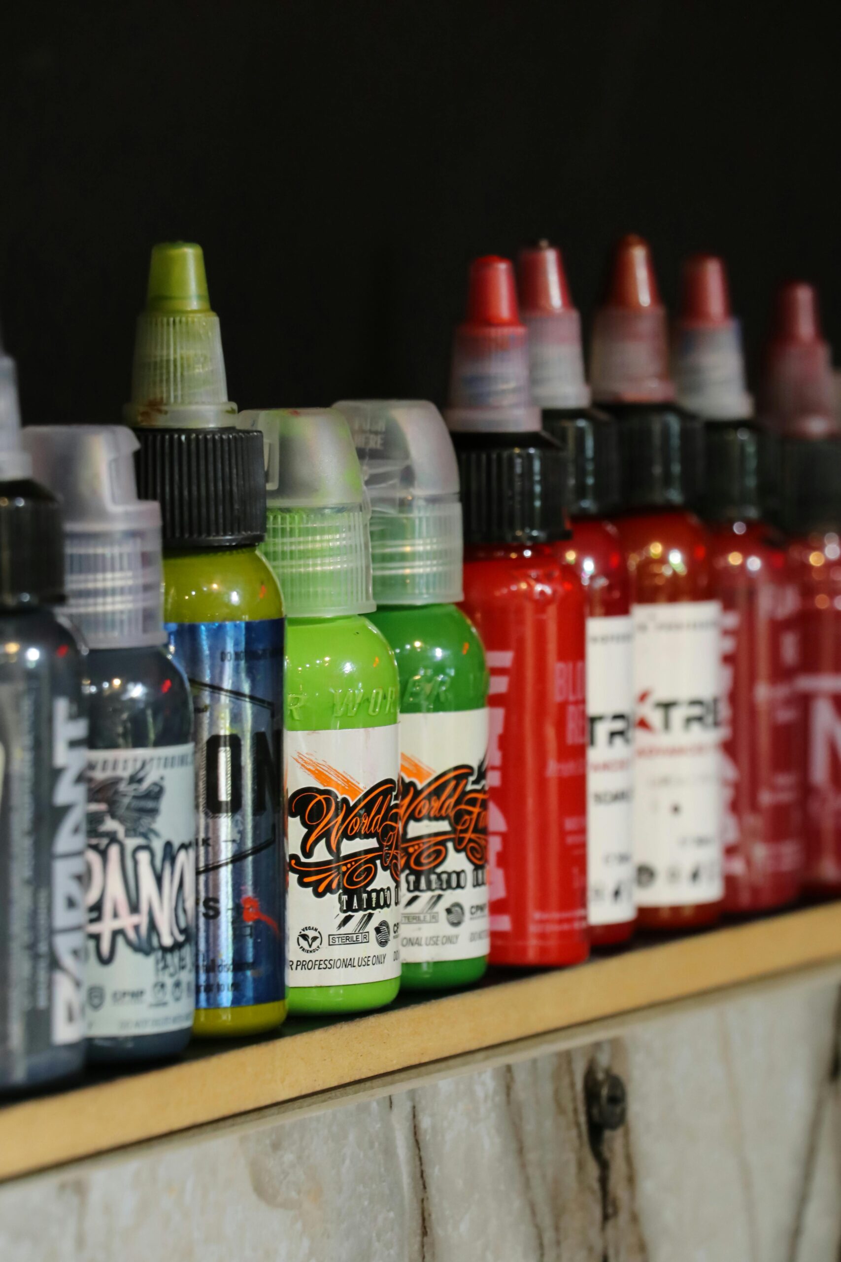 A vibrant collection of tattoo ink bottles arranged neatly on a shelf indoors.