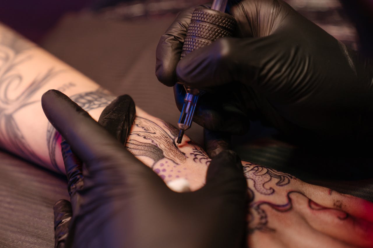 The Art of Drawing Readers In: Your attractive post title goes here Close-up of a tattoo artist applying ink on a client's arm with precision.