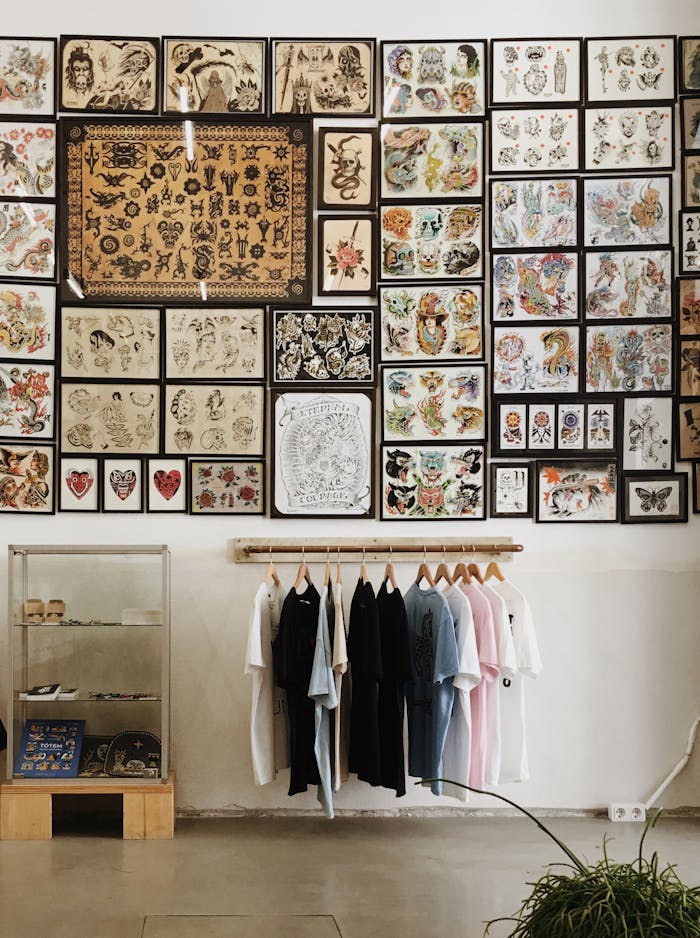 A tattoo parlor interior featuring framed artwork and hanging T-shirts, displaying a creative atmosphere.